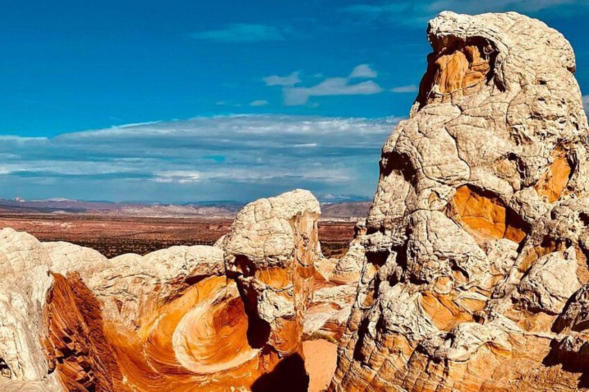 A rugged rock formation with layered strata, a clear blue sky, and a distant landscape. 5