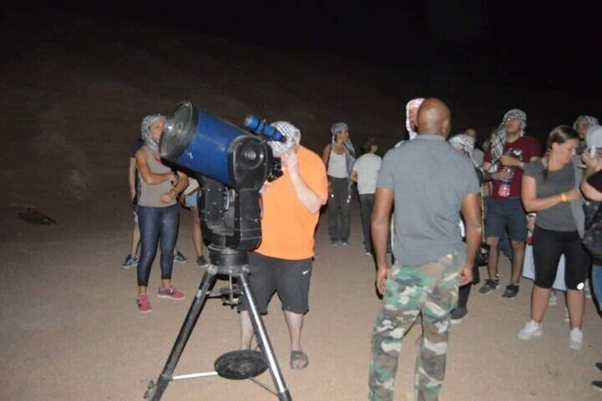A group of people observing through a large telescope. 5