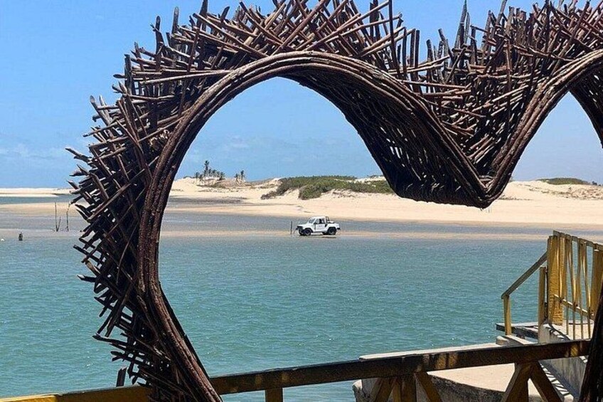 A wooden arch structure over a beach with a vehicle in the background. 5