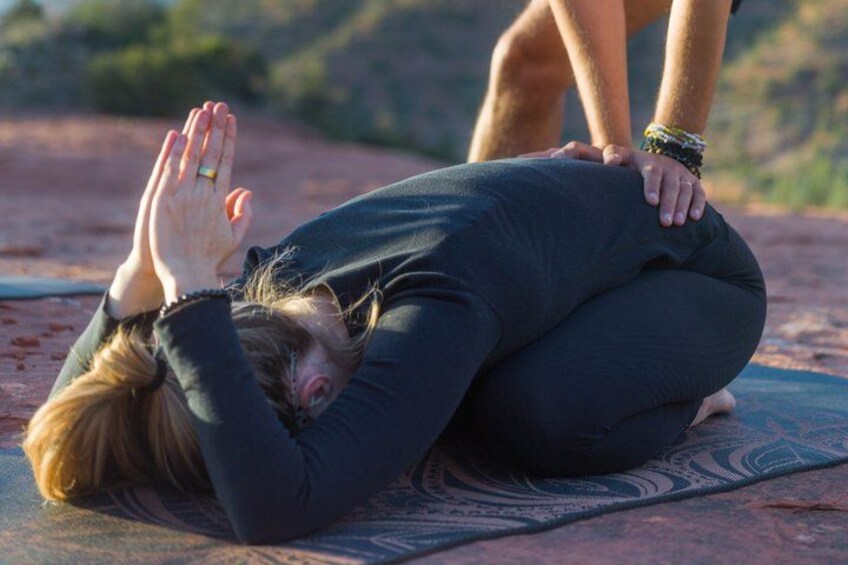 En person som utför en yogaposition på en matta utomhus. 2
