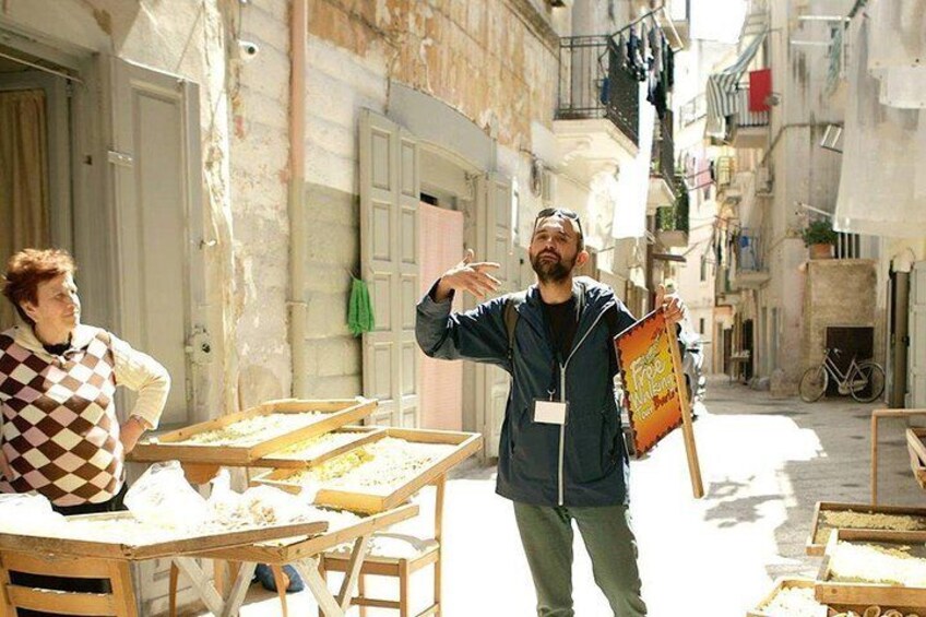 Un vendeur ambulant avec une enseigne, des tables en bois sur lesquelles sont disposés des aliments, et un vélo dans une ruelle étroite. 4