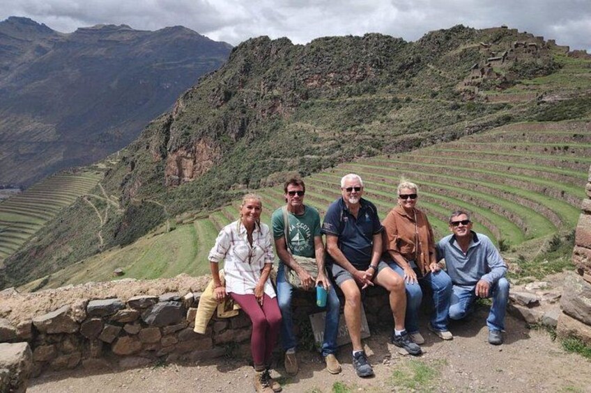 Un gruppo di persone sedute su un muro di pietra con vista su campi a terrazze e montagne. 4
