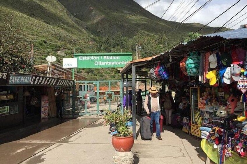 Un'area di mercato con un cartello che indica 'Estación / Station Ollantaytambo' e un caffè chiamato 'Café Perla'. 2