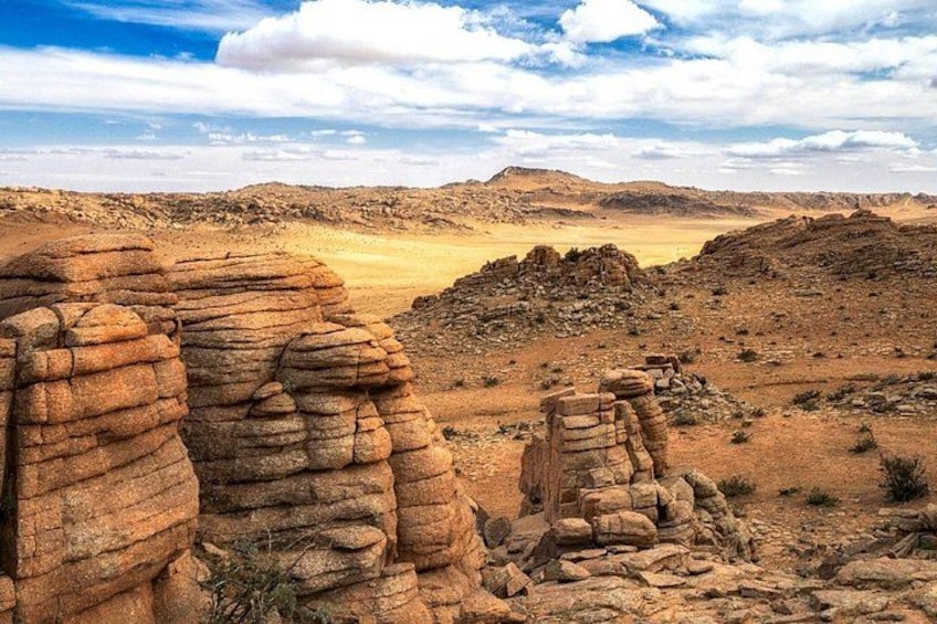 A desert landscape with rock formations and distant hills. 3