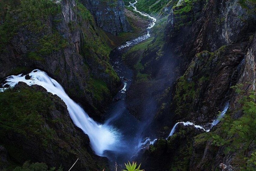 A waterfall cascading down a steep, rocky gorge surrounded by lush greenery. 5