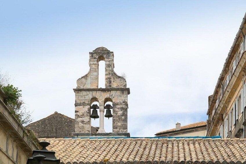 A bell tower with two bells, a tiled roof, and a building with a curved facade. 4