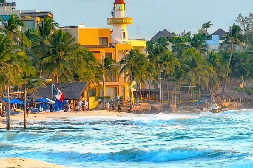 Una playa con palmeras, un faro y un edificio con un letrero. 5