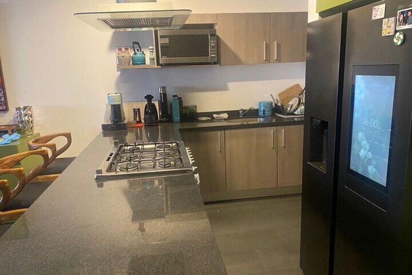 A modern kitchen with a gas stove, microwave, refrigerator, and wooden cabinets. 5