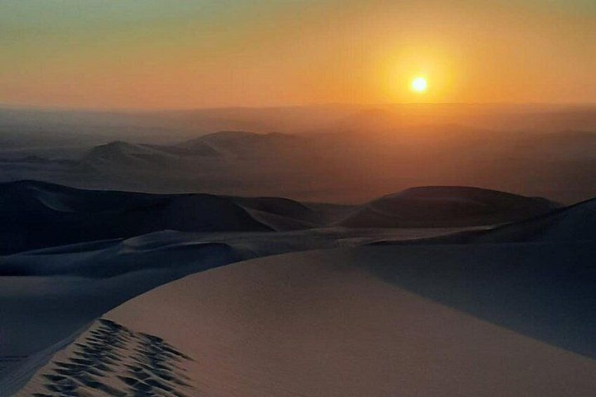 A desert landscape with sand dunes and a setting sun. 3