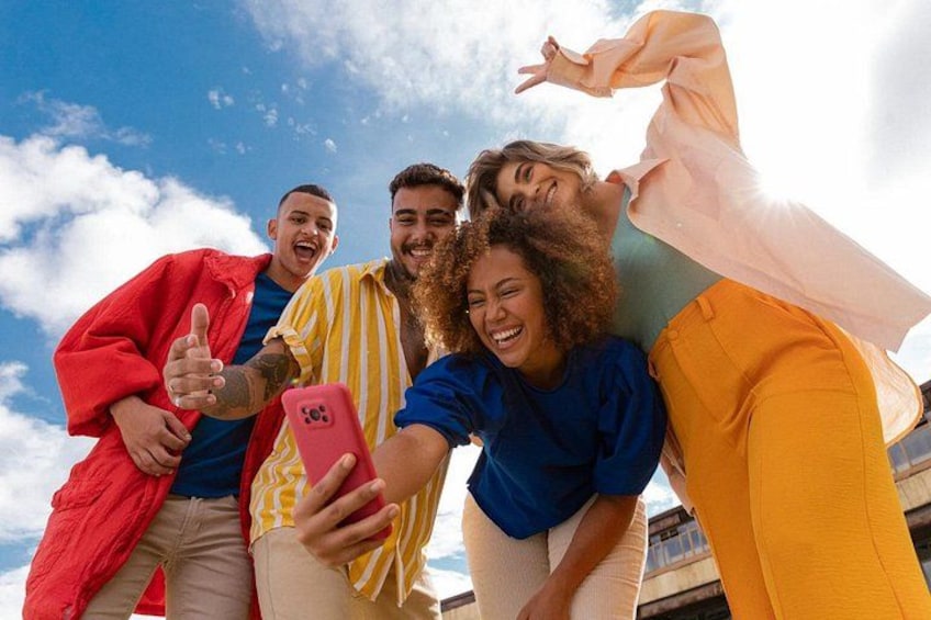 Un groupe de personnes prenant un selfie à l’extérieur, avec un ciel dégagé en arrière-plan. 4