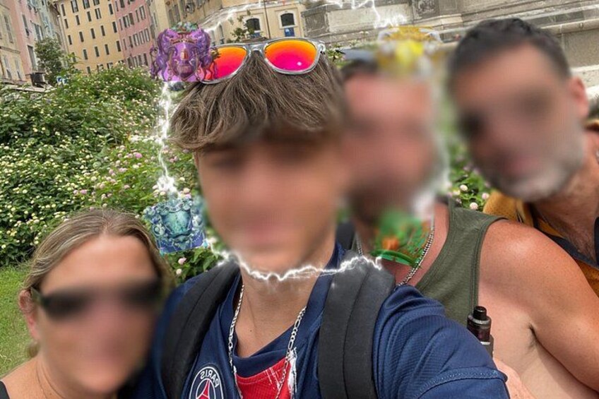 Une personne porte un sac à dos et des lunettes de soleil. On aperçoit un bâtiment en arrière-plan, ainsi qu’un espace vert parsemé de fleurs. 3