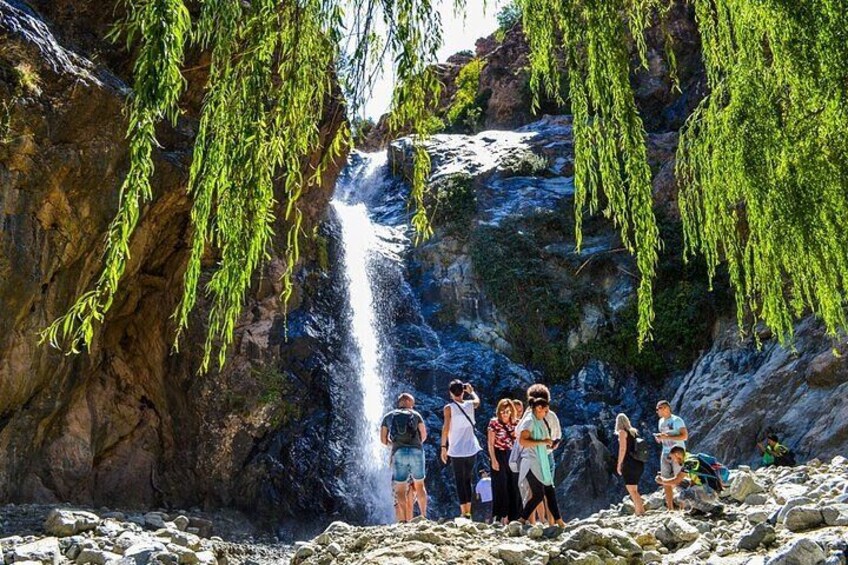 A waterfall with people standing on rocks below. 4