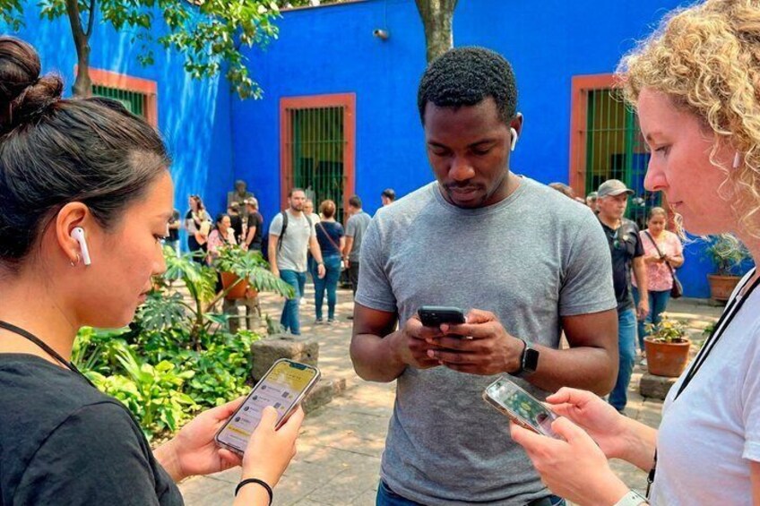 People standing outdoors, some looking at their phones. 2