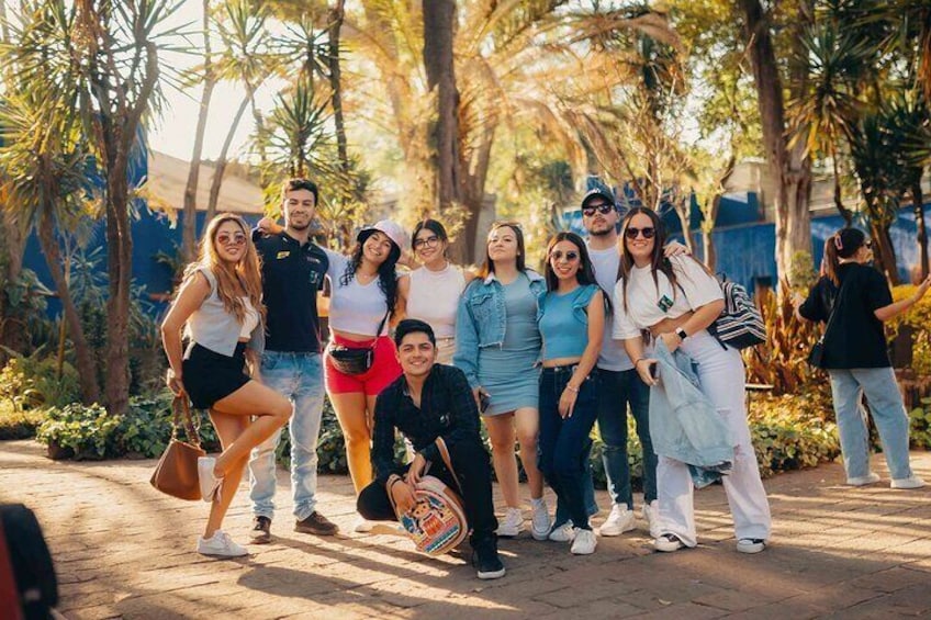 A group of people posing outdoors with palm trees and a paved walkway in the background. 5