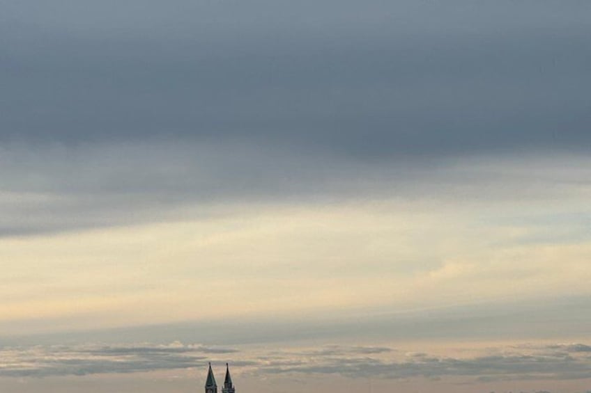 A cloudy sky above a landscape with two spires. 3