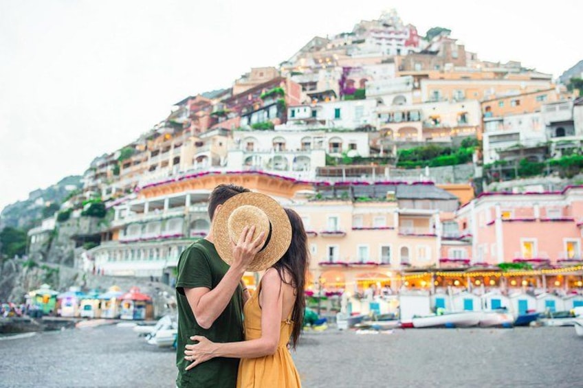 A couple embracing on a beach with colorful buildings in the background. 5