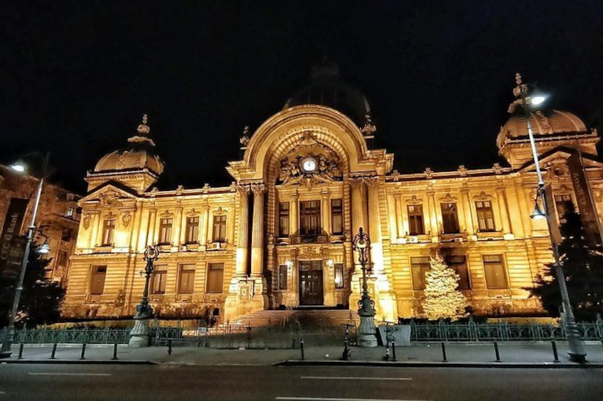 A grand, illuminated building with a dome and arched entrance, surrounded by a fence and street lamps. 3