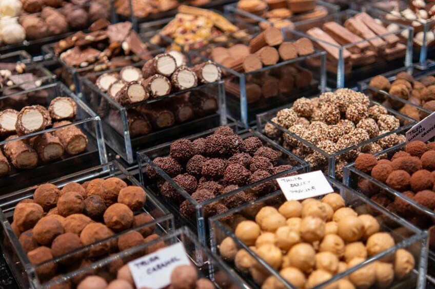 A variety of chocolates displayed in clear containers. 3