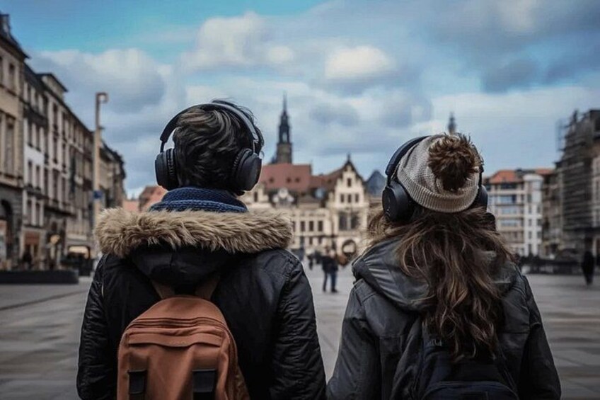 Twee mensen lopen over een stadsstraat met historische gebouwen op de achtergrond. 4