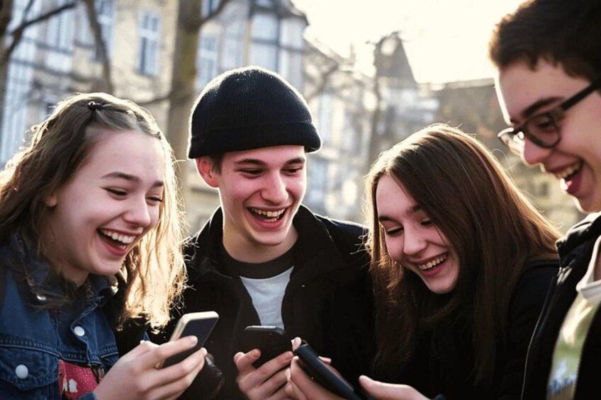 Een groep mensen die buiten staat en naar een smartphone kijkt. 5