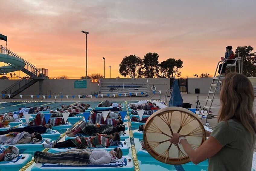 A poolside with boats and a person holding a drum. 1
