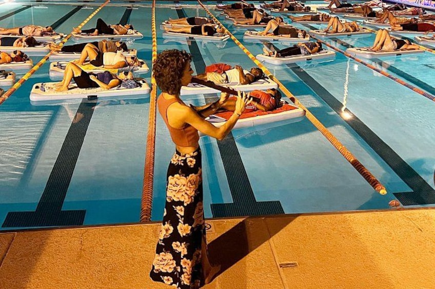 A swimming pool with lanes and people lying on floatation devices. 2