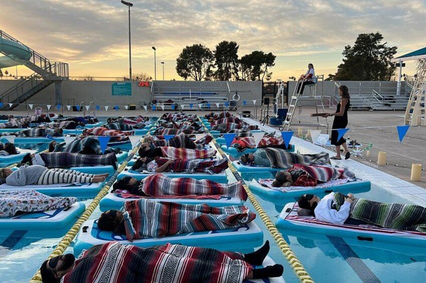People lying on inflatable mattresses on a dock at sunset. 4