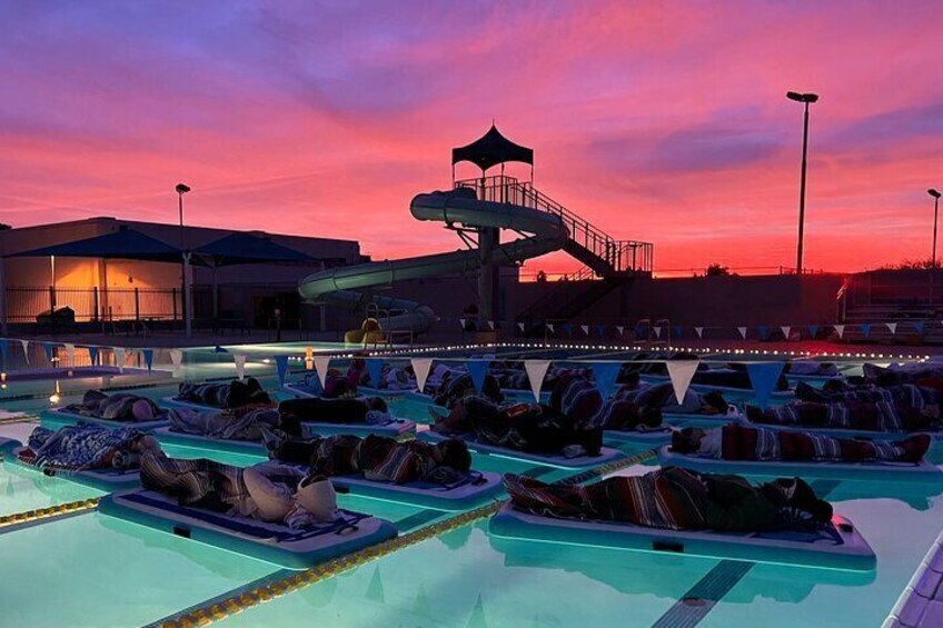 A water park at dusk with a water slide and lounge chairs by the pool. 5