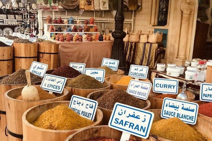 A spice market with various spices displayed in wooden containers, labeled with names in multiple languages. 2