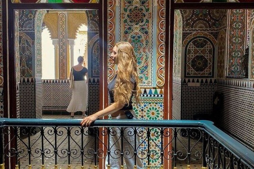 Una persona de pie en un balcón con paredes de azulejos ornamentales y barandilla. 4