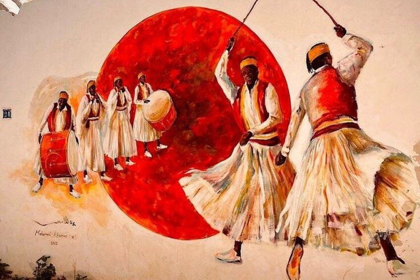 Un grupo de personas vestidas con atuendo tradicional tocando tambores, con un gran círculo rojo al fondo. 3