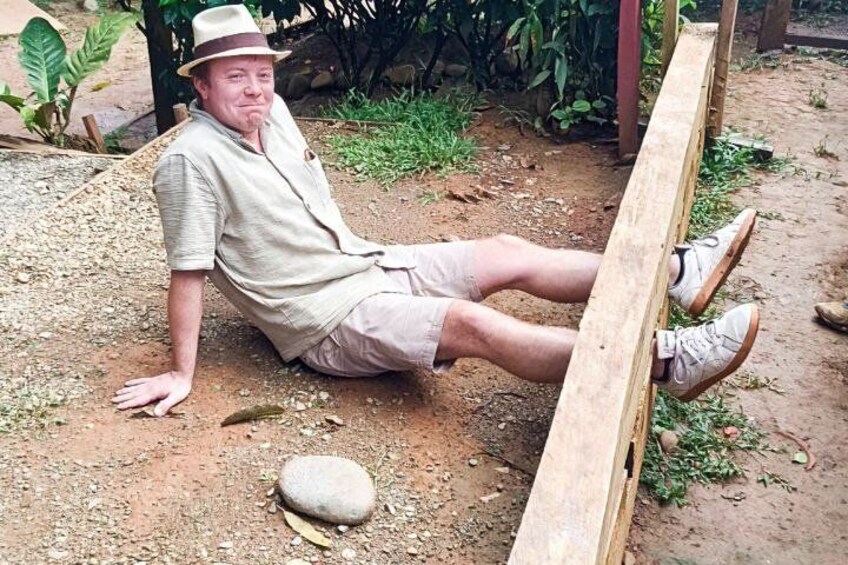 A person sitting on the ground with a wooden structure behind them. 3