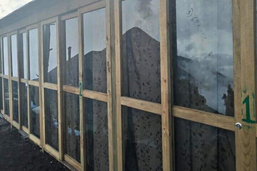 Una hilera de ventanas con marcos de madera que reflejan un paisaje montañoso. 3