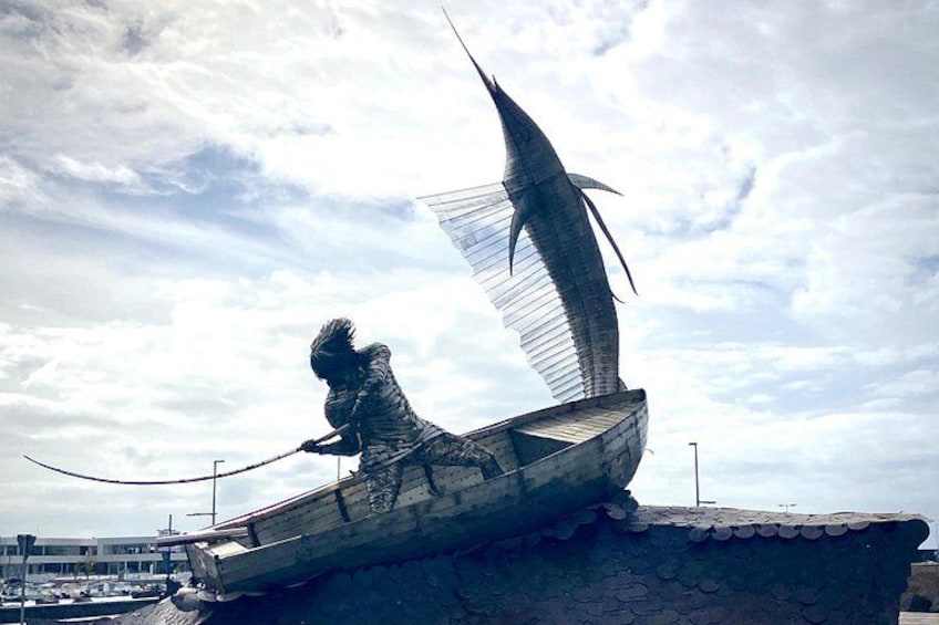A sculpture of a person fishing in a boat with a large fish. 2
