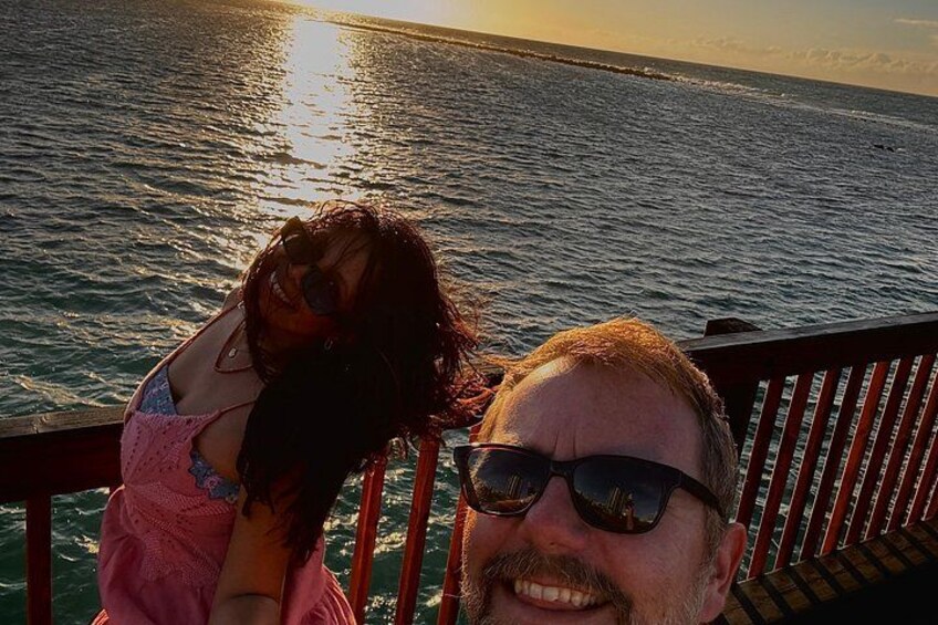 A person wearing a pink top and sunglasses, standing on a boat with a railing. 1