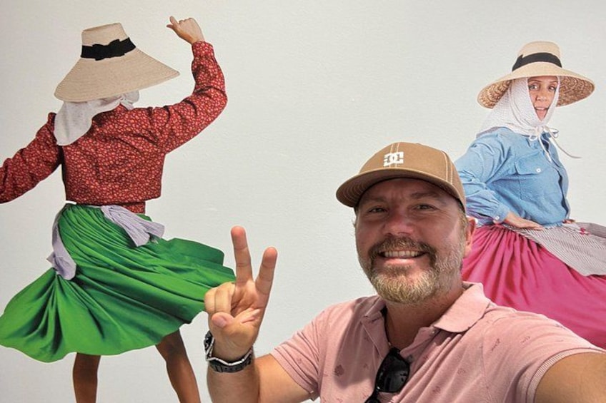 A person in a pink shirt and cap, making a peace sign. 5