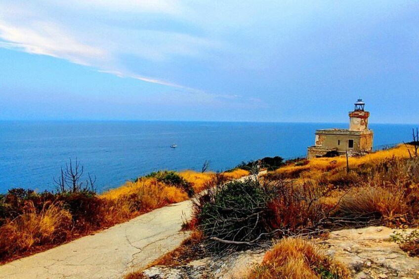 A coastal landscape with a lighthouse, a narrow path, and the sea. 3