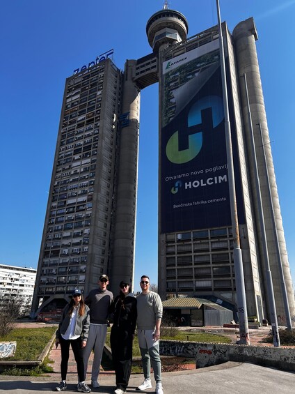 A group of people standing in front of a building with a large advertisement for Holcim. 2