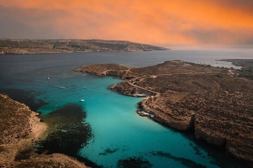 Un paysage côtier caractérisé par une eau turquoise et limpide, un terrain rocheux et une ligne de côte lointaine. 1