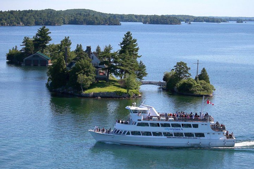Un navire de croisière blanc, rempli de passagers, une petite île avec des maisons et un pont reliant l’île au continent. 4