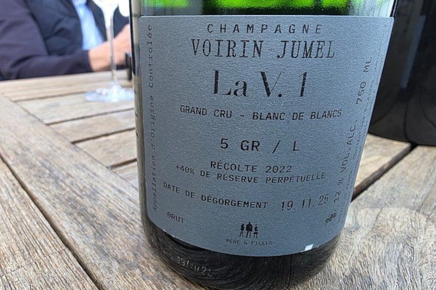 Eine Flasche La V.1 Champagner auf einer Holztischplatte. 2