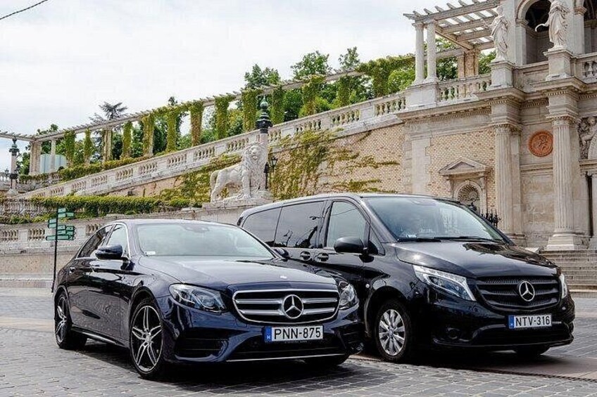 Two black Mercedes-Benz cars parked in front of a historic building with ornate architecture. 2