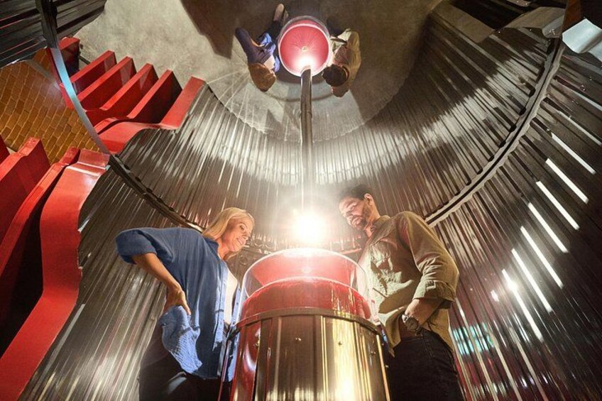 A metallic cylindrical structure with a red and black design, surrounded by a curved metallic wall. 3