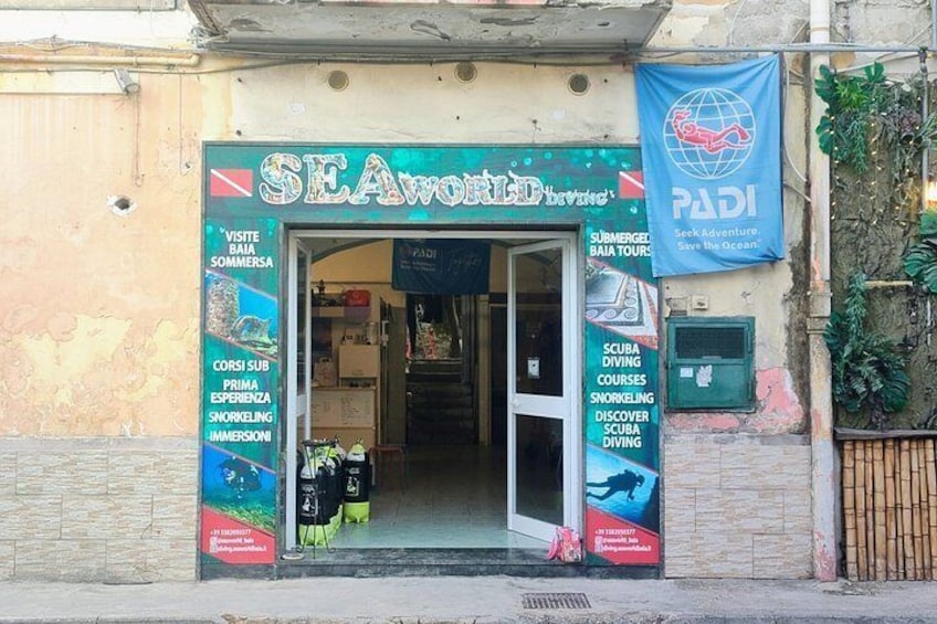 Un escaparate con un cartel de SEAWORLD Buceo y un banderín de PADI. 5