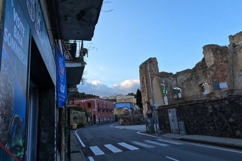 Una calle con un paso de peatones, un letrero azul y un edificio con un cartel que dice 'VISITE BAJA SOMERSA'. 2