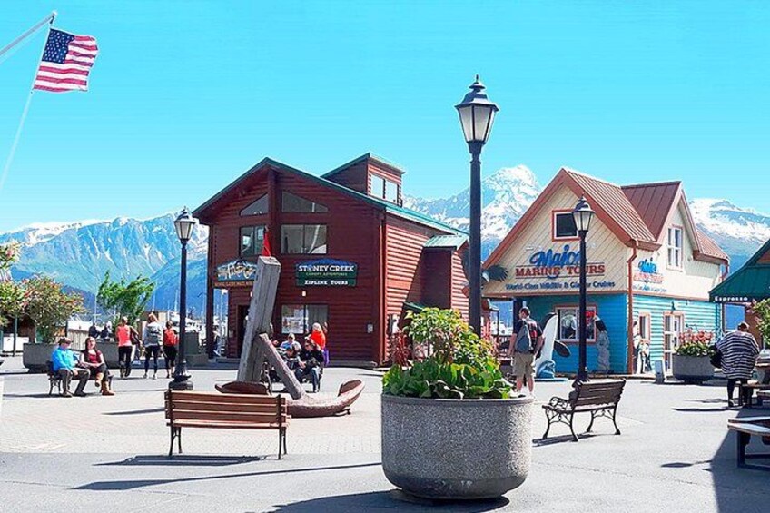 A town square with benches, a large planter, and buildings with signs for a marina and a restaurant. 4