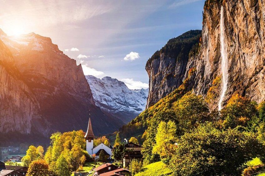 Eine Berglandschaft mit einem Wasserfall, einer Kirche und einem Tal. 3