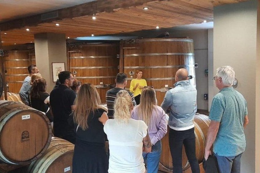 A group of people inside a building with wooden barrels and a large wooden door. 3
