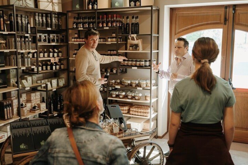 A person in a white shirt pointing at shelves stocked with various bottles and jars in a store. 2