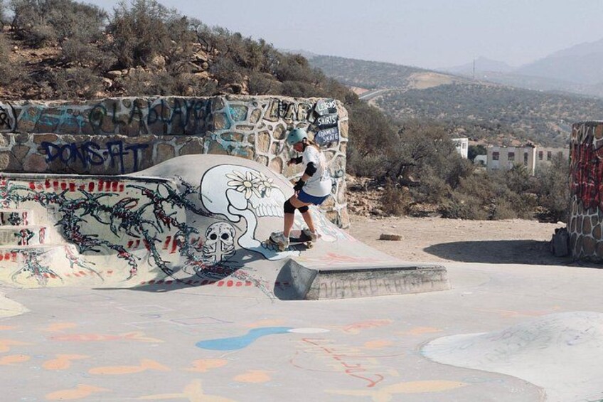Iemand skatet in een skatepark vol graffiti, met een bergachtig landschap op de achtergrond. 4